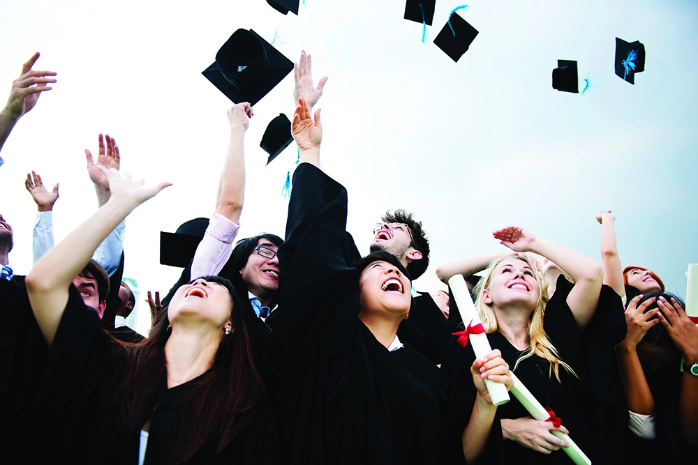 group-diverse-grads-2026 Group of diverse graduates throwing caps into the air