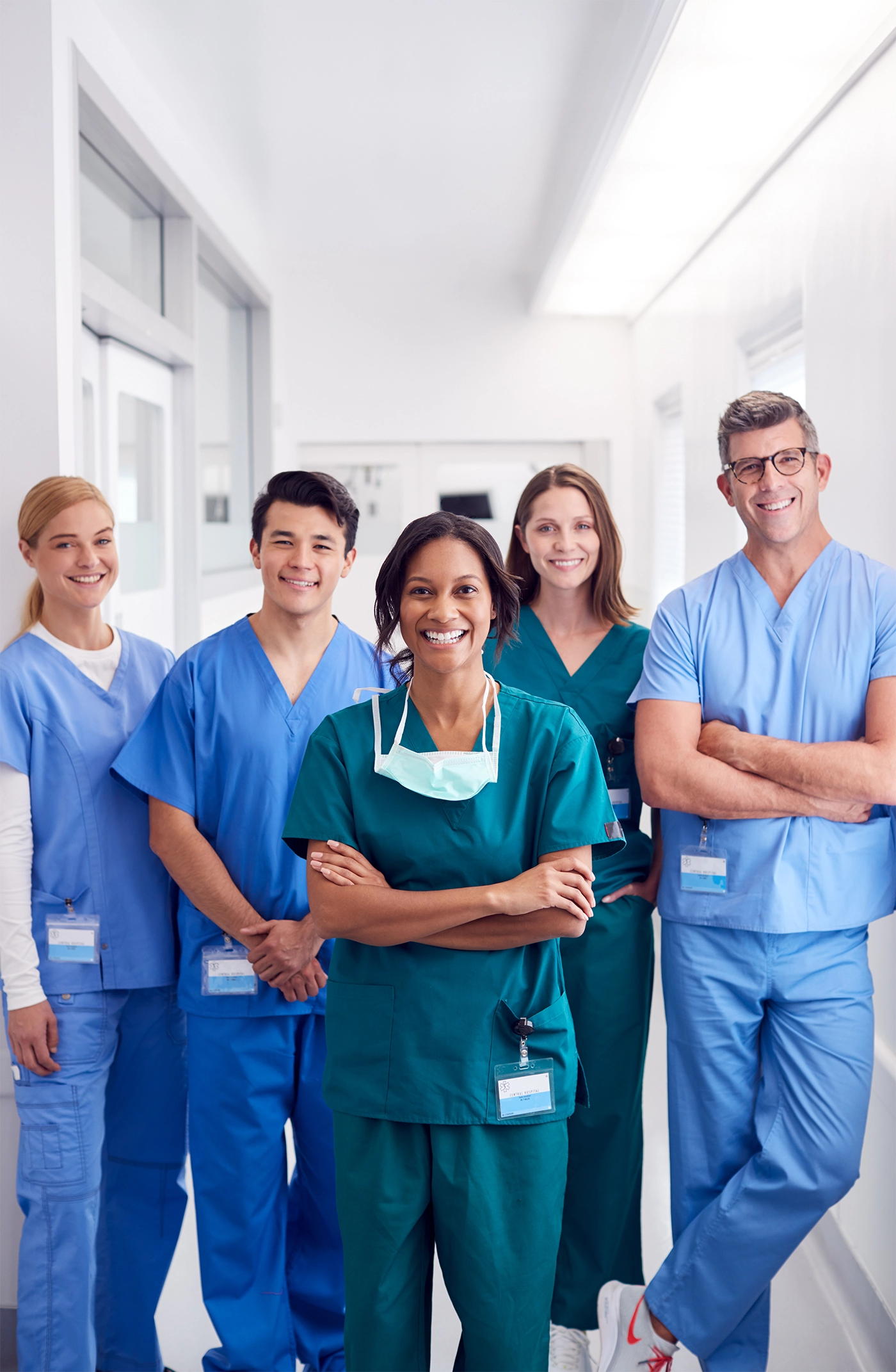 Healthcare student wearing scrubs and standing in hallway with pencil and clipboard